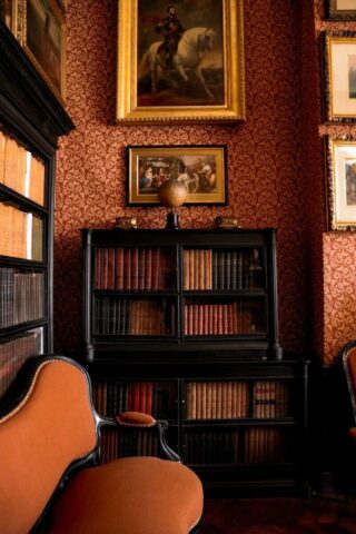 a room with a chair, bookshelf and a painting on the wall