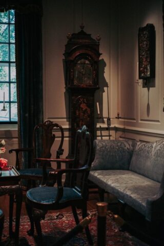 Antique grandfather clock and chairs in dimly lit room.