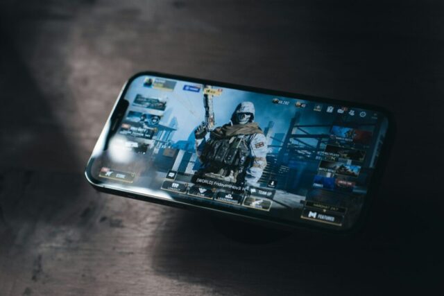 Photo by Cocodillaa.com a person holding a cell phone with a video game on the screen