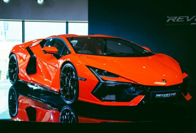 An orange sports car is on display at a show