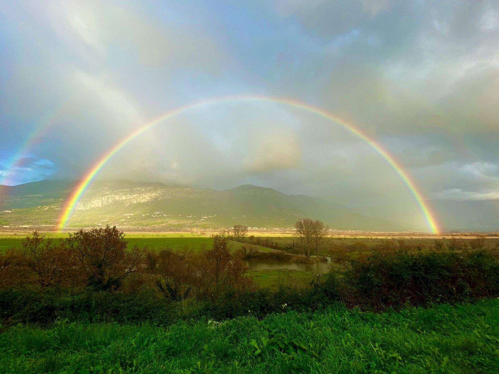 two rainbows in the sky over a green field