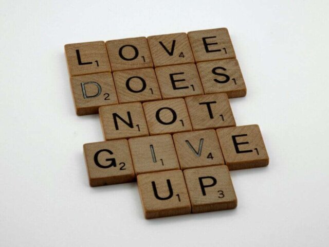 a scrabble tile with the words love does not give up