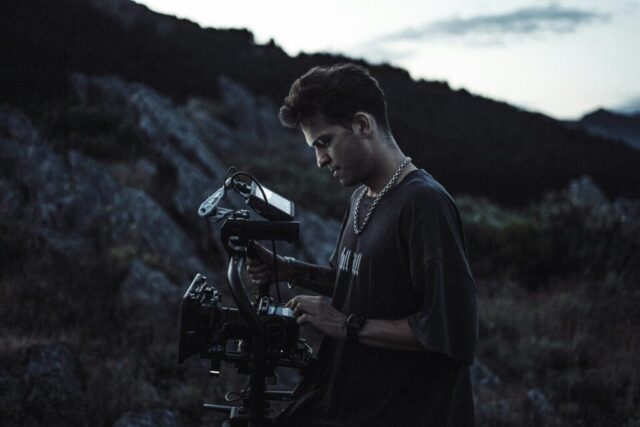 Photo by Cocodillaa.com Filmmaker operating camera on rocky hillside at dusk