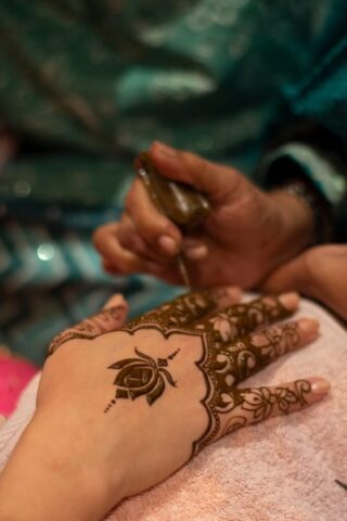 Henna artist applying intricate design to hand.
