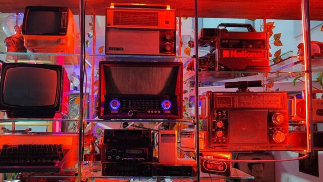 Vintage electronics are displayed on shelves with vibrant lighting.