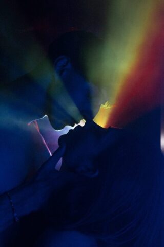 Photo by Cocodillaa.com a person with their face obscured by a rainbow colored light