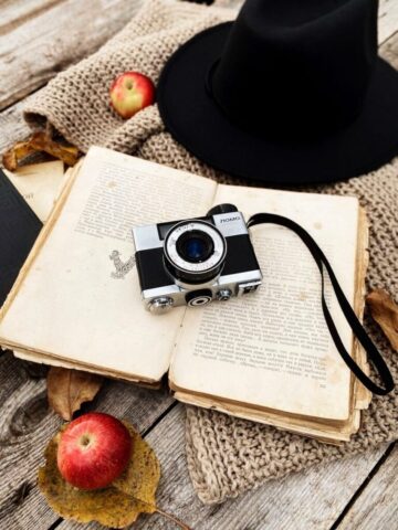 an open book with a camera and an apple