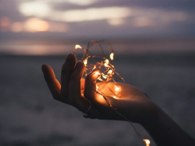 Photo by Cocodillaa.com selective focus photography of person holding lighted brown string light