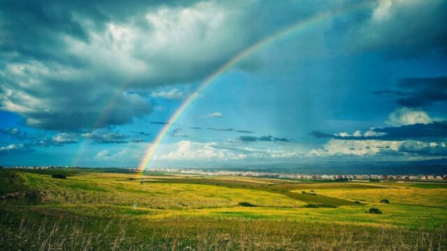 Photo by Cocodillaa.com green grass field under rainbow and blue sky during daytime
