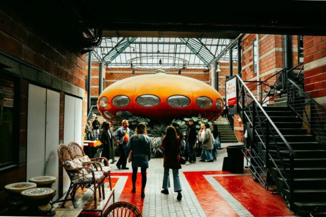 Orange futuristic structure inside a building with people