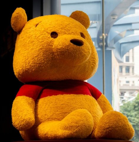 A large yellow teddy bear sitting on top of a table