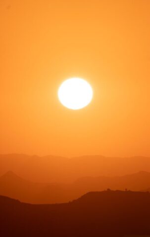 the sun is setting over a mountain range