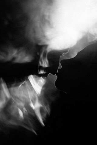 Photo by Cocodillaa.com a black and white photo of a person smoking a cigarette