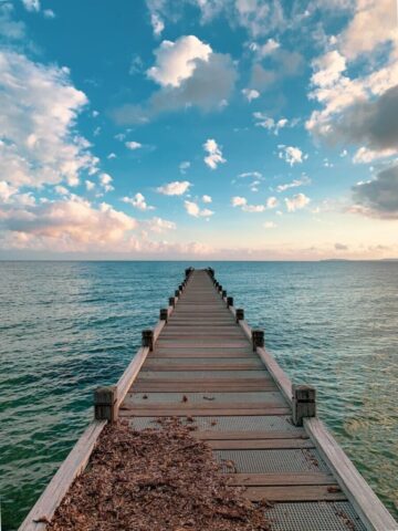 brown wooden dock on sea under blue sky during daytime