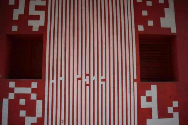 Red wall with white vertical stripes and pixelated designs.